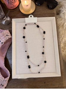 Detail of a double-layer long sweater necklace with white pearls and black gemstones