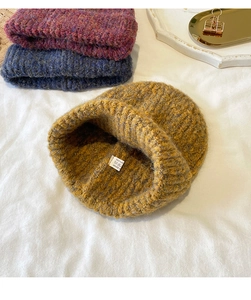 Macro detail of mixed color knit beanies in yellow, purple and blue acrylic yarn