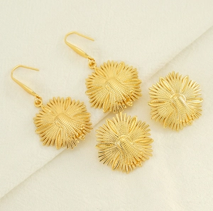 Detailed macro view of golden daisy flower earrings and pendants on a soft fabric texture
