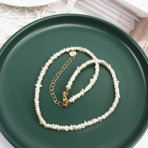 French vintage baroque pearl necklace with gold-plated clasp on a dark green ceramic tray