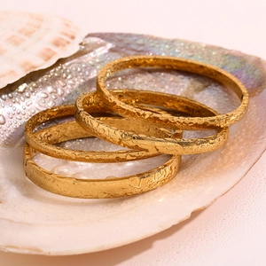 Dettaglio di 4 bracciali placcati in oro 18K con texture martellata in una conchiglia