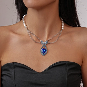 Elegant pearl necklace with blue crystal teardrop pendant shown on a model neck