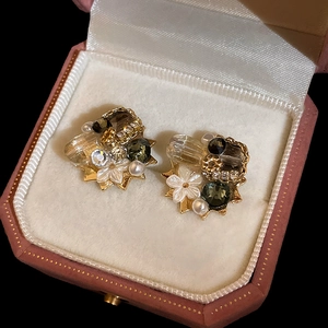Detailed close-up of crystal flower earrings with pearls in a luxury jewelry box