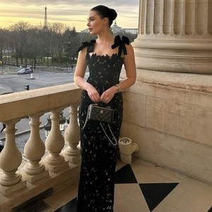 Detail of elegant black lace maxi dress with velvet bow straps on a balcony in Paris