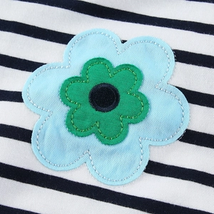 Detalle de un vestido a rayas para niña con parche bordado de flores de dibujos animados.