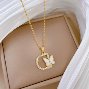 Macro shot of gold necklace featuring D-letter pendant with shell butterfly and crystals
