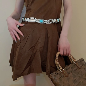 Detail of bohemian white woven belt featuring turquoise stone and wooden bead accents