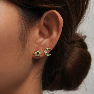 Close-up of gold 925 silver asymmetric sun and moon stud earrings on model's ear