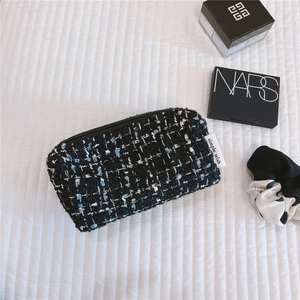 Macro view of blue and black tweed cosmetic bag with Simple Wish label and zipper