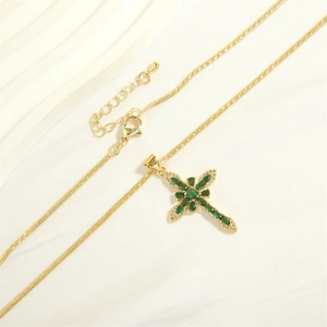 Detail of 18K gold-plated cross pendant with green marquise stones on satin fabric