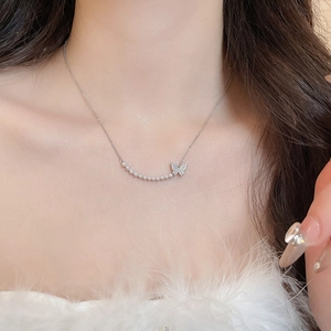 Close-up of silver butterfly necklace with small pearls worn by a model in soft lighting