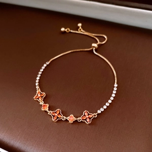 Close-up of 18K gold-plated bracelet with orange clover charms and inlaid diamonds