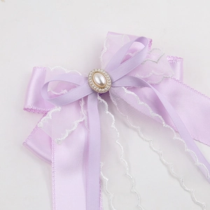 Detail of lavender ribbon hair clip with mesh lace, large oval pearl and long streamers
