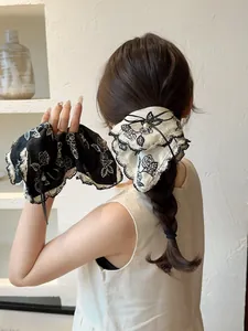 Detail of rose print hair scrunchie with lace trim, white pearls and a delicate black bow