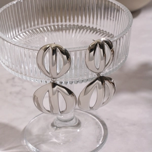 Macro view of geometric silver hollow round stud earrings on a textured glass holder