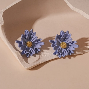 Detail of purple flower earrings with gold pistils displayed in a minimalist plaster bowl