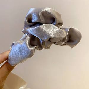 Detail of silver grey satin fabric hair claw with elegant pleated cloud texture held by hand