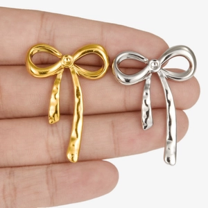 Minimalist 304 stainless steel bow knot earrings in gold and silver finish on a finger