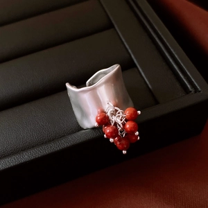 Macro detail of wide irregular silver ring with red beaded cluster on black leather