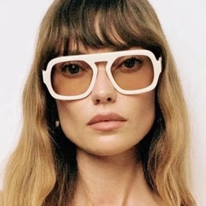 Fashionable oversized white sunglasses with transparent orange lenses on a female model