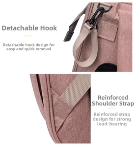 Detail of pink diaper bag showing removable metal hooks and reinforced shoulder strap stitching