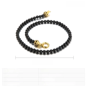 Detail of punk skull bracelet featuring black glass beads and gold stainless steel finish