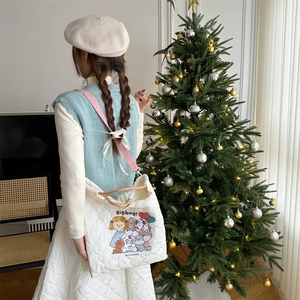 Close-up of quilted white tote bag with cartoon embroidery and pink straps in a cozy setting
