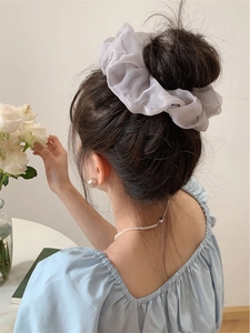 Close-up of a large white organza scrunchie on a soft bun for a romantic hair look