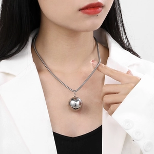 Silver snake chain necklace with round sphere pendant shown on a model wearing white suit