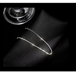 Macro detail of S925 silver shimmering chain with round ring clasp on black leather