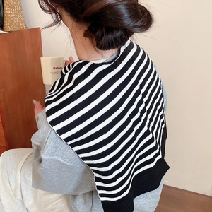 Close-up of black and white striped knitted shawl draped over a gray sweatshirt