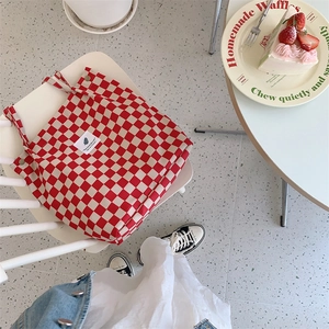 Close-up of red checkerboard corduroy tote bag handle with snap button on white chair