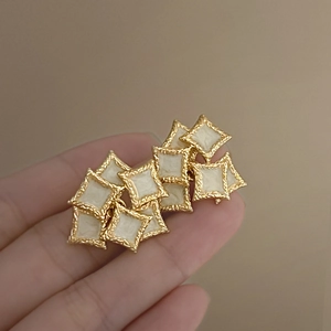 Detailed view of vintage gold-tone relief earrings with cream enamel diamond-shaped tiles