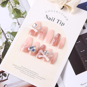 Macro view of gradient pink press-on nails with white roses, rhinestones and lace bows