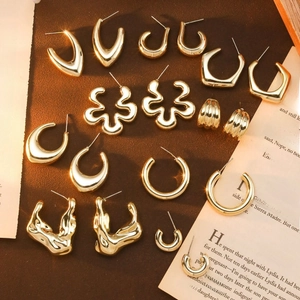 Chic gold C-shaped flower and irregular acrylic hoop earrings on a vintage book background