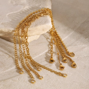 Détail de bracelets en perles dorées avec charmes en zircon sur socle pierre