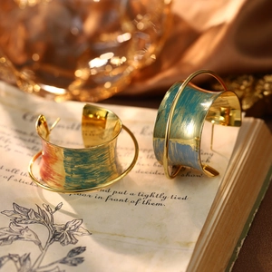 Close-up of wide enamel hoop earrings with colorful brushed paint on vintage book