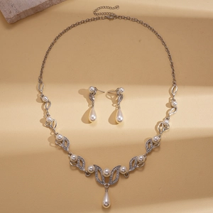 Elegant silver leaf jewelry set with white pearls and rhinestones on gold background