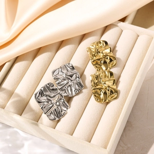 Square textured earrings in gold and silver finish on soft velvet display tray