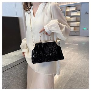 Detail of black sequin evening bag with gold metal handle and chain strap on model