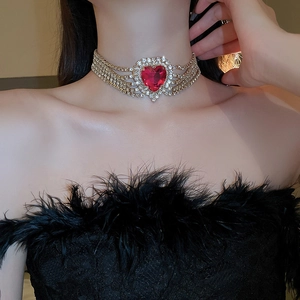 Close-up of golden choker with five rows of rhinestones and a large red heart gemstone