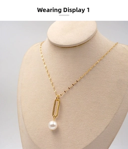 Detail view of a gold chain necklace featuring a textured ring and a large white pearl pendant