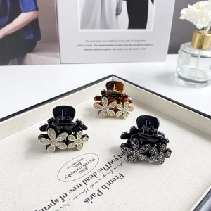 Detailed view of three mini floral hair claws with rhinestones on a jewelry tray