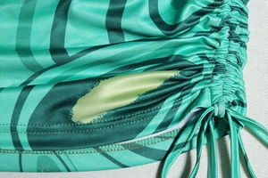 Detail of green printed halter dress featuring side drawstring and ruched fabric texture