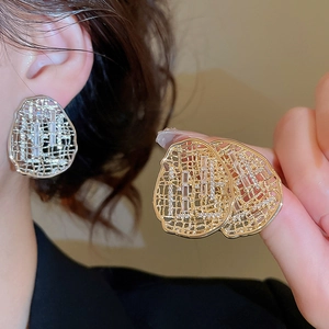 Détail de boucles d'oreilles ovales creuses en métal avec zircons en or et argent