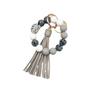 Detail of silicone bead keychain with grey tassel and gold lobster clasp on white background