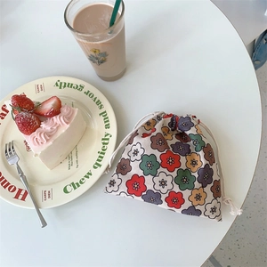 Detail of floral drawstring pouch with cute fabric pattern and storage cord on table