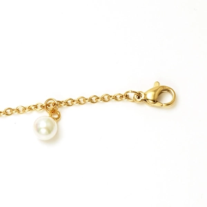 Detailed macro view of 18K gold-plated lobster clasp and white pearl pendant detail
