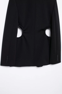 Detail of black blazer featuring waist cut-outs and four buttons on sleeve cuffs