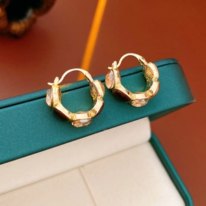 Macro shot of gold hoop earrings with champagne resin stones on a green jewelry box